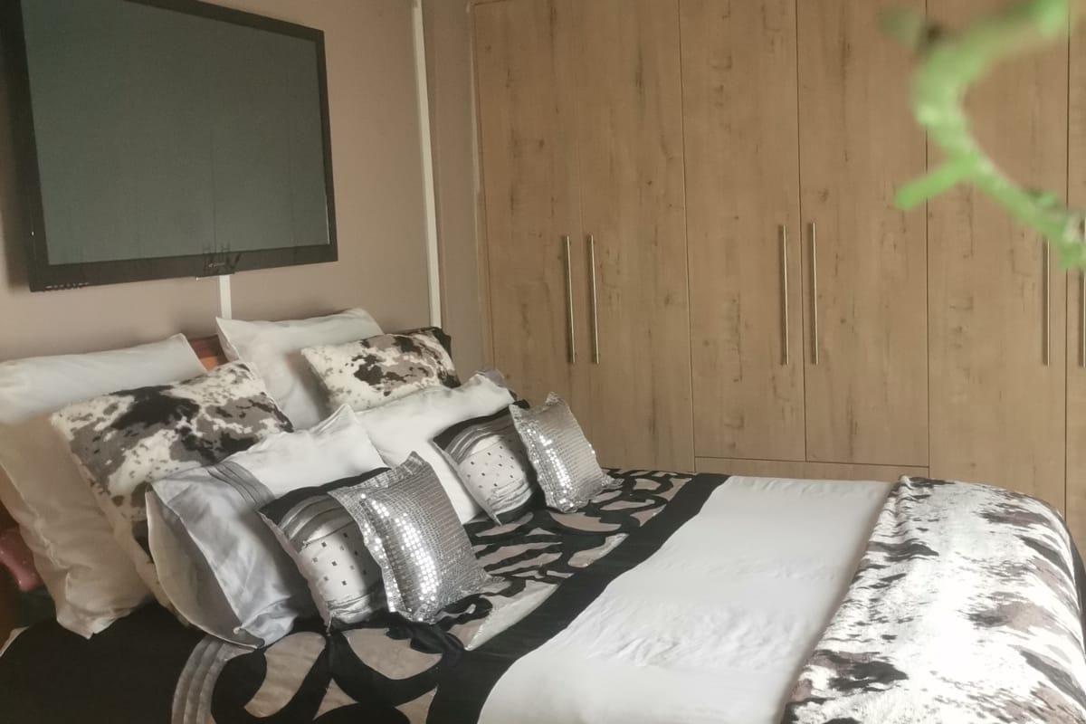 A bedroom featuring built-in wooden wardrobes, decorative ceiling coving, and a central ceiling rose with a flush mount light fixture.