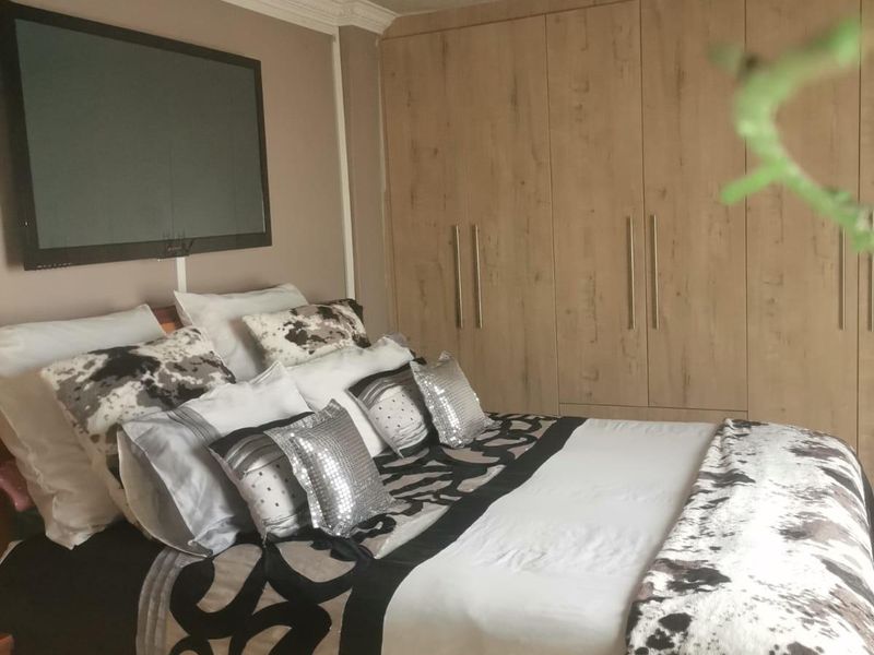 A bedroom featuring built-in wooden wardrobes, decorative ceiling coving, and a central ceiling rose with a flush mount light fixture.
