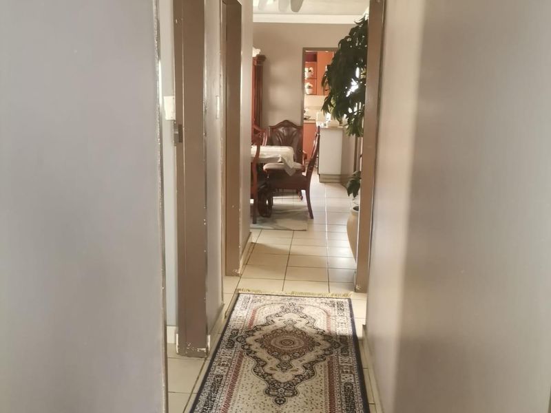 A central hallway featuring tiled flooring and decorative ceiling detailing, providing access to adjacent living areas.