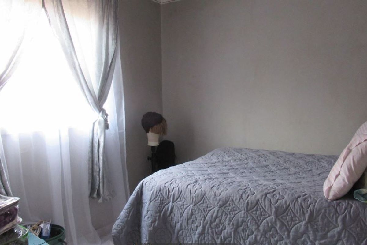 A simple bedroom featuring neutral wall tones and natural light from the window.