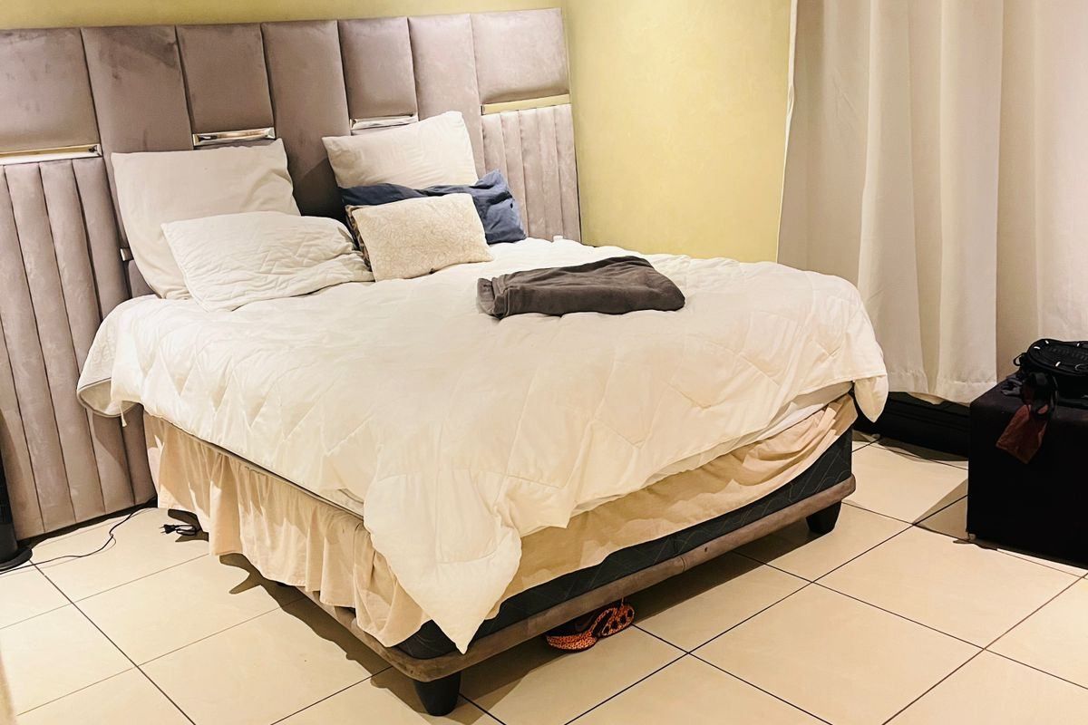 A bedroom featuring neutral tiled flooring and recessed ceiling lighting, providing a functional space for rest.