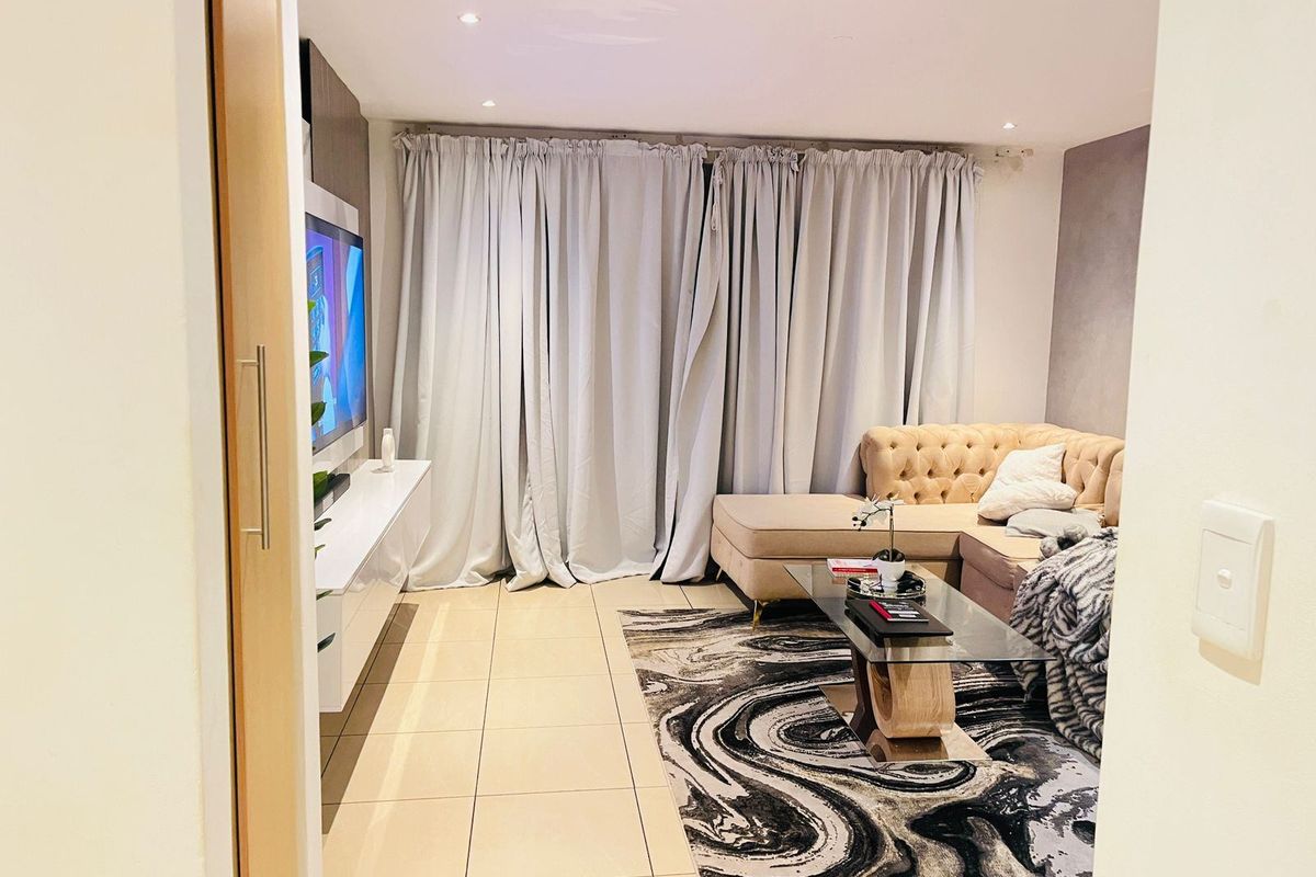 A well-maintained living room featuring tiled flooring, recessed ceiling lighting, and a built-in media console, offering a clean and functional living space.