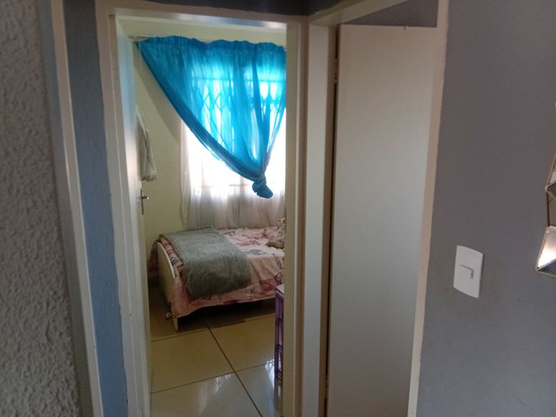 A view through a doorway into a bedroom featuring tiled flooring and a window fitted with a security gate.