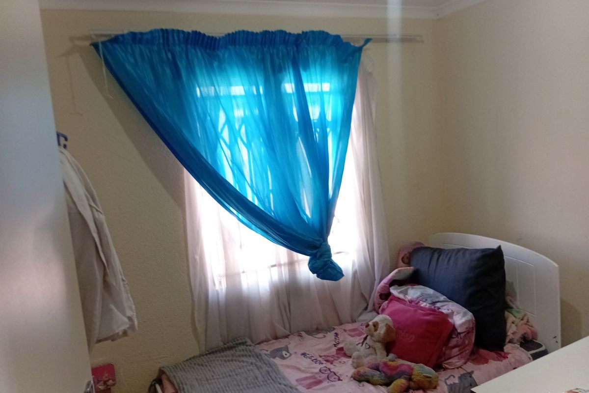 A standard bedroom featuring a window with security bars and a curtain rod, providing basic natural light and functional space.