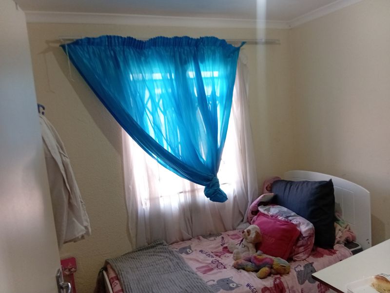 A standard bedroom featuring a window with security bars and a curtain rod, providing basic natural light and functional space.