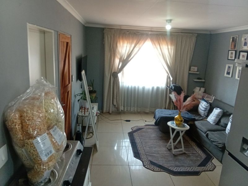 A living room featuring tiled flooring and neutral wall tones, providing a functional space with natural light through the window.