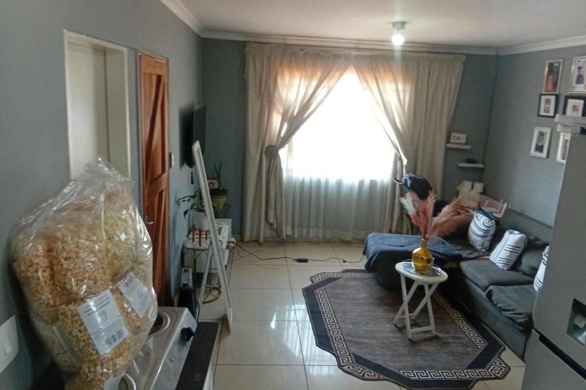 A living room featuring tiled flooring and neutral wall tones, providing a functional space with natural light through the window.