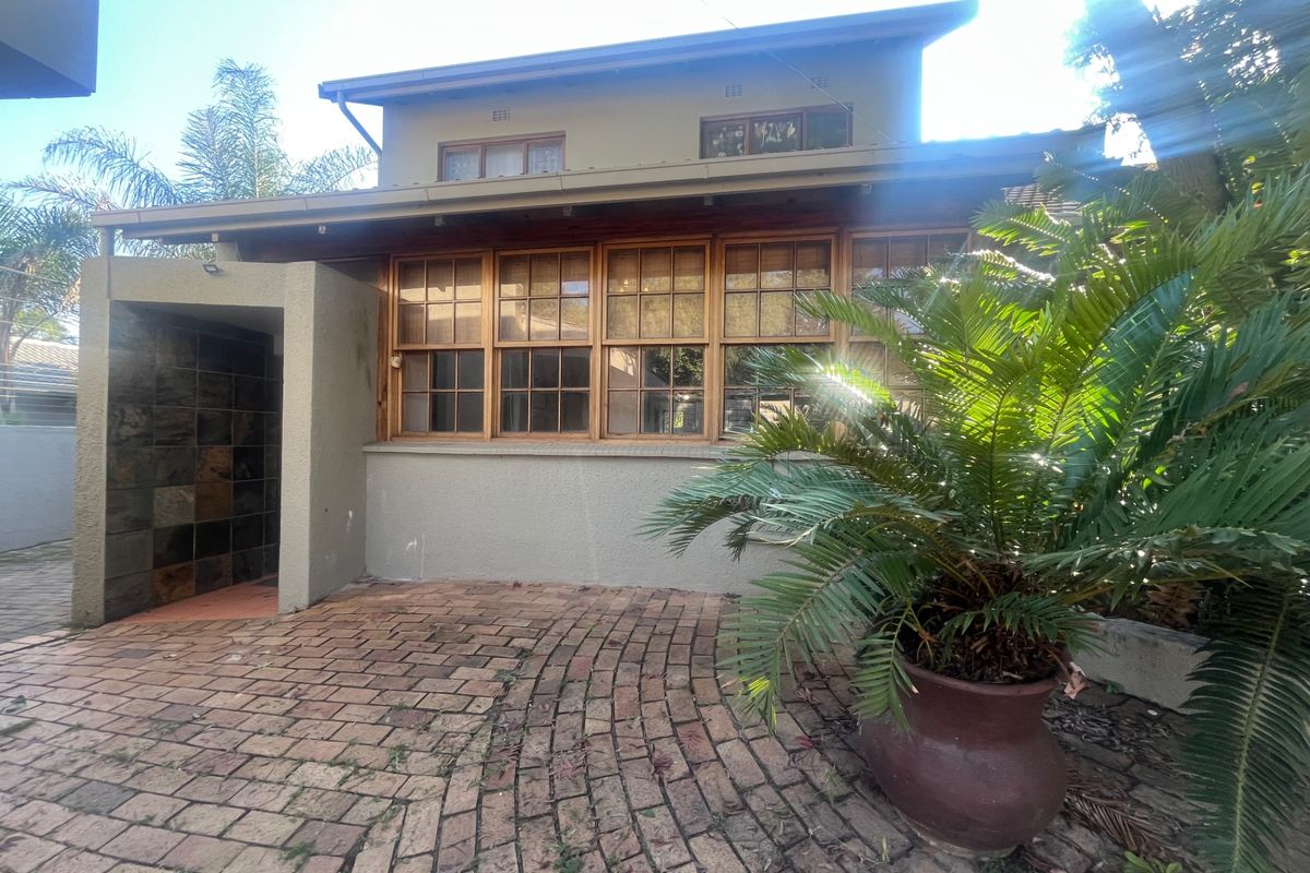 Rear exterior view of the property featuring a brick paved patio area, timber framed windows, and a slate-tiled entrance alcove.