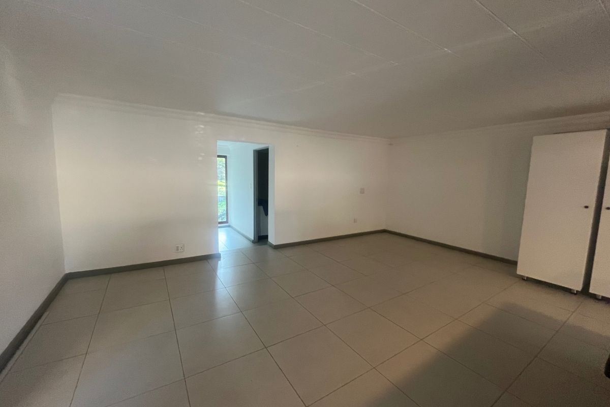 A spacious, empty bedroom featuring neutral tiled flooring and a built-in cupboard, offering a clean and versatile living space.