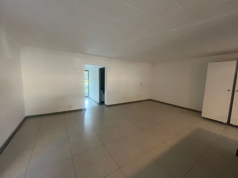A spacious, empty bedroom featuring neutral tiled flooring and a built-in cupboard, offering a clean and versatile living space.