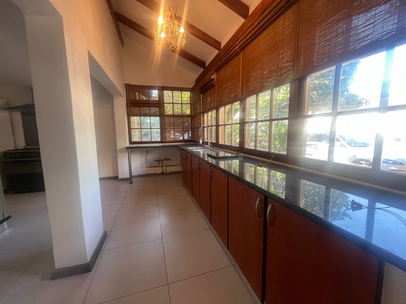 A spacious kitchen area featuring granite countertops, exposed timber beams, and large windows, offering a bright and functional layout ready for modern updates.