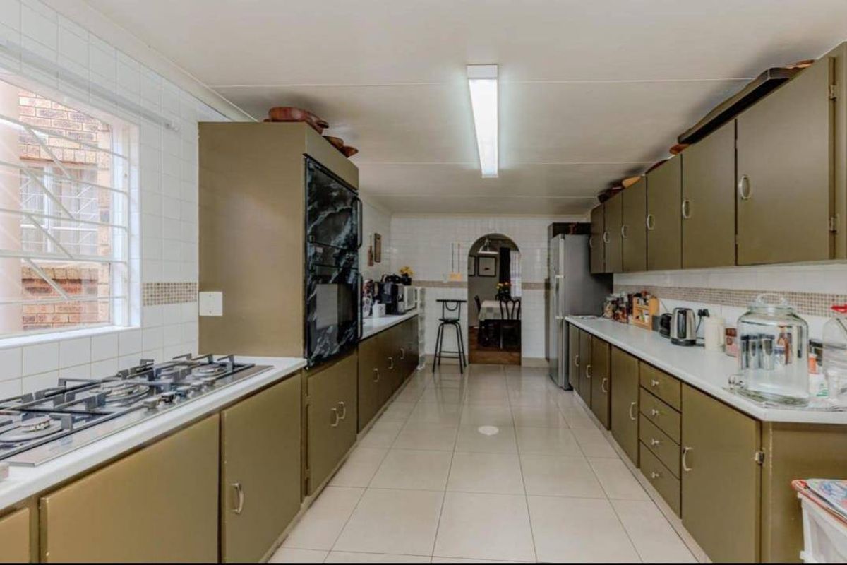 A functional galley-style kitchen featuring extensive built-in cabinetry, a gas hob, and a built-in oven with tiled splashbacks and flooring.