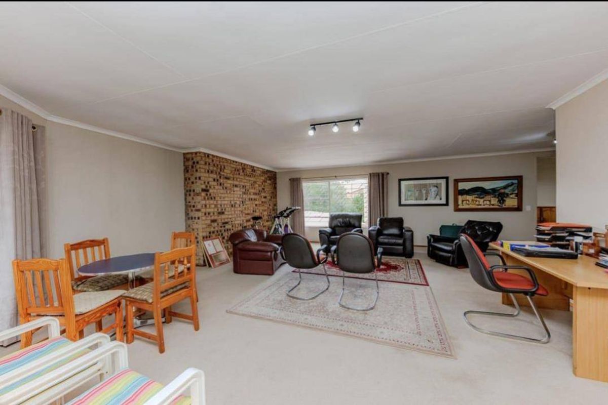 Spacious living area featuring an exposed brick accent wall, neutral carpeting, and sliding glass doors providing natural light.