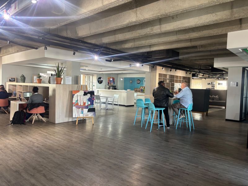 Spacious open-plan commercial area featuring exposed concrete ceilings, modern track lighting, and integrated service counters suitable for a collaborative office or cafe environment.