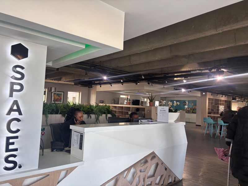 Modern commercial reception area featuring a contemporary desk, exposed concrete ceiling, and professional track lighting in a well-maintained office environment.