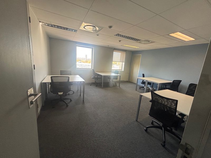A functional commercial office space featuring a suspended ceiling, recessed lighting, and carpeted flooring, suitable for a professional work environment.