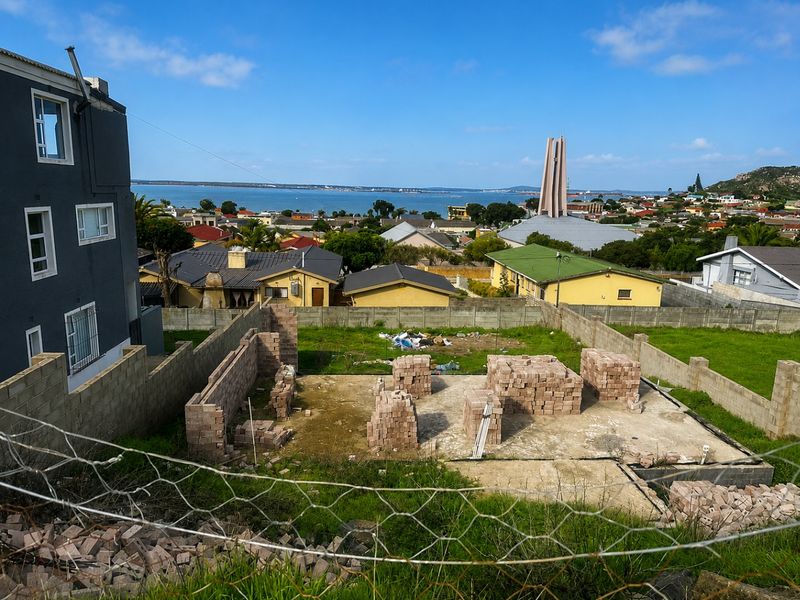 Vacant residential plot featuring a concrete foundation and stacked brickwork, offering scenic coastal and neighbourhood views.