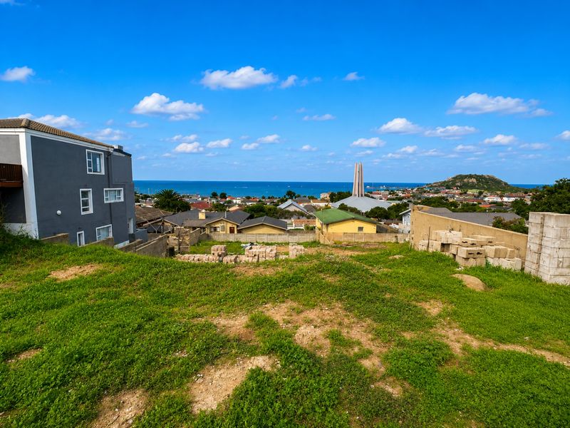 A vacant residential plot featuring a gentle slope, grassy terrain, and expansive coastal and neighbourhood views, ideal for future development.