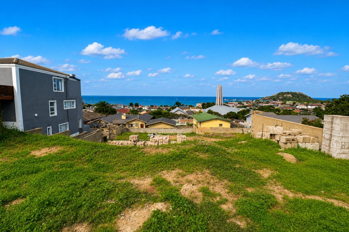 A vacant residential plot featuring a gentle slope, grassy terrain, and expansive coastal and neighbourhood views, ideal for future development.
