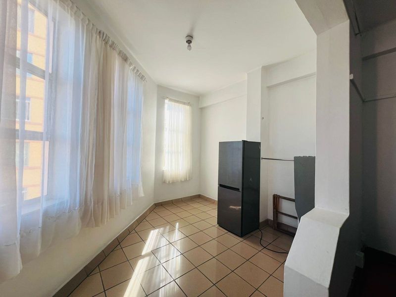 A bright, tiled utility space featuring large windows, suitable for a laundry area or home office setup.