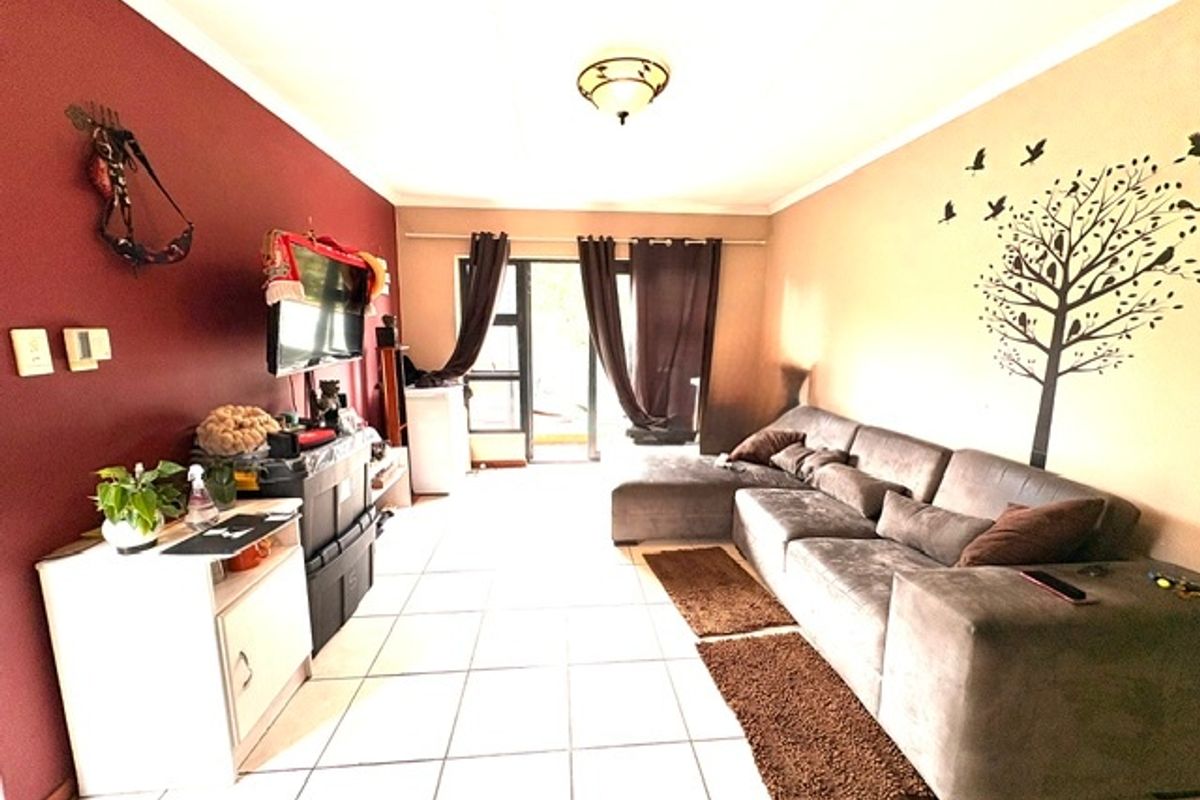 A living room featuring tiled flooring and a sliding glass door providing access to the exterior.