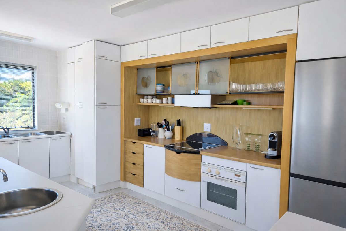 A well-maintained kitchen featuring white and wood-tone cabinetry, integrated appliances, laminate countertops, and a functional layout with ample storage space.