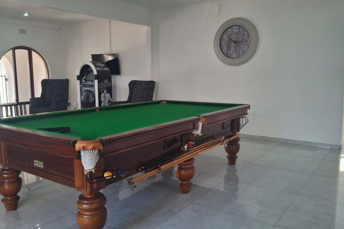 Spacious living area featuring polished tiled flooring and an arched doorway, currently utilized as a recreational space with a billiard table.