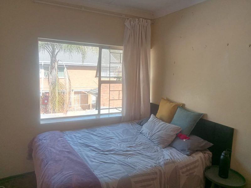 A bedroom featuring a large window with natural light and wall surfaces requiring cosmetic attention.