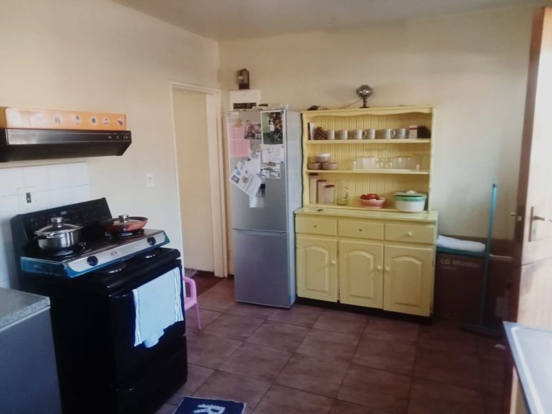 A functional kitchen area featuring tiled flooring, a tiled splashback, and an extractor fan, offering a practical layout for daily cooking needs.