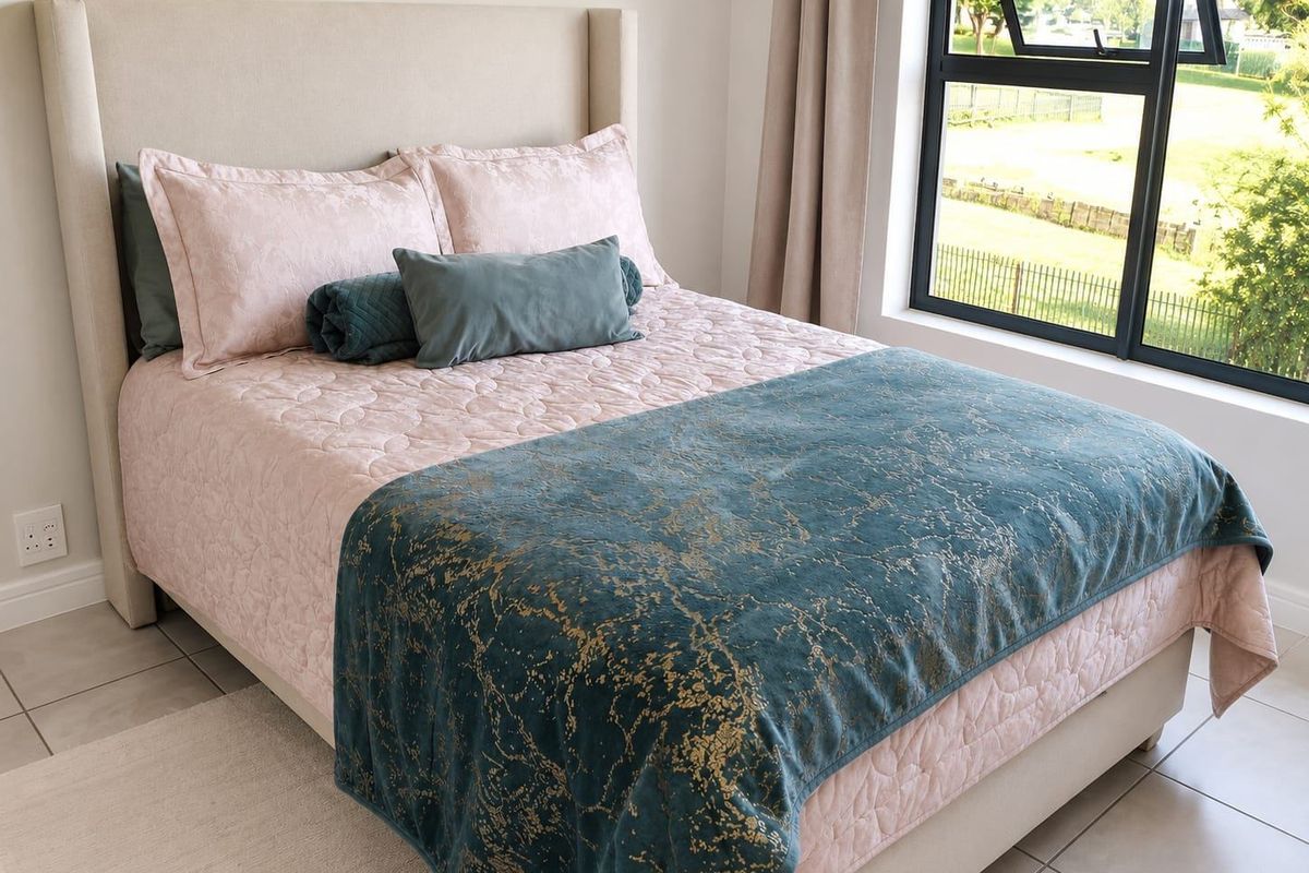 A well-maintained bedroom featuring modern black aluminium window frames and neutral tiled flooring, offering a bright and comfortable living space.