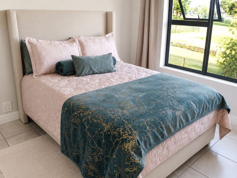 A well-maintained bedroom featuring modern black aluminium window frames and neutral tiled flooring, offering a bright and comfortable living space.