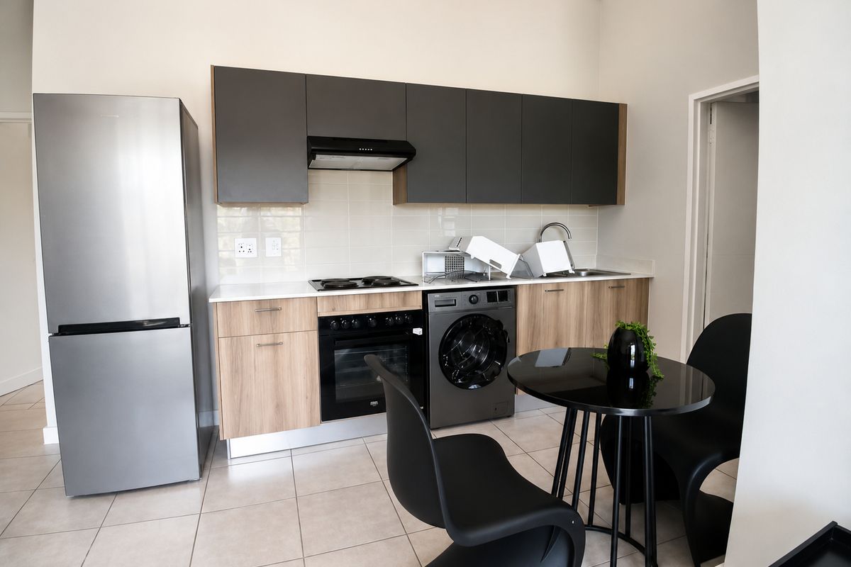Modern kitchen featuring two-tone cabinetry, integrated electric hob and oven, extractor fan, and tiled flooring with a clean, contemporary finish.