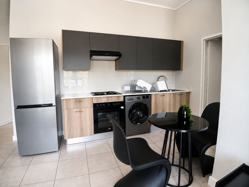 Modern kitchen featuring two-tone cabinetry, integrated electric hob and oven, extractor fan, and tiled flooring with a clean, contemporary finish.