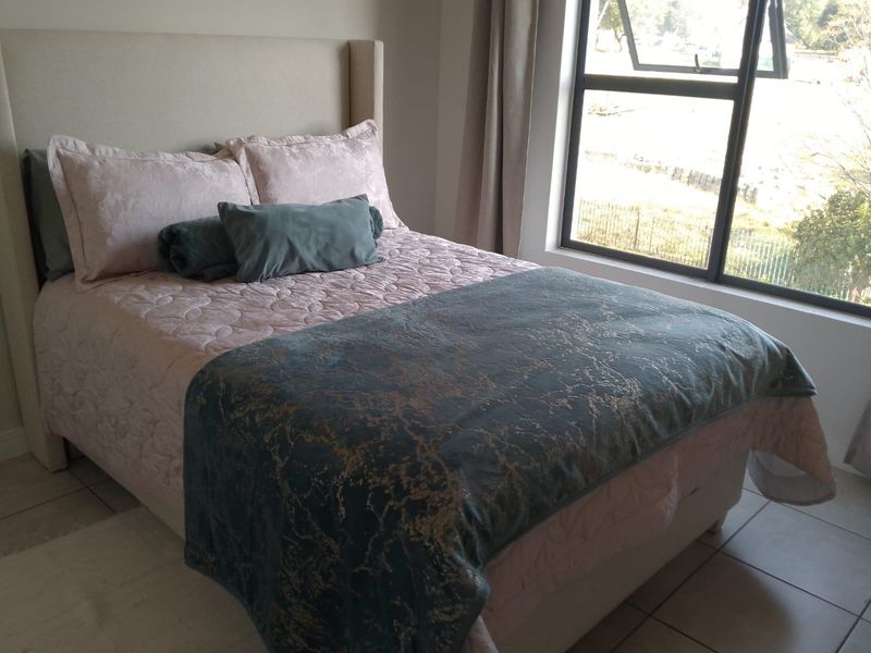 A well-lit bedroom featuring tiled flooring and a large window providing natural light and exterior views.