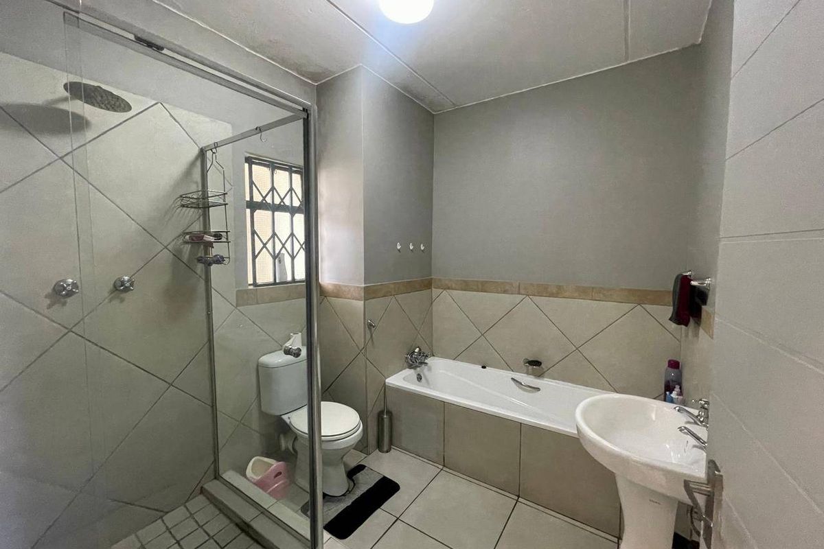 A functional bathroom featuring a separate glass shower enclosure, a built-in bathtub, and a pedestal basin with neutral wall and floor tiling.