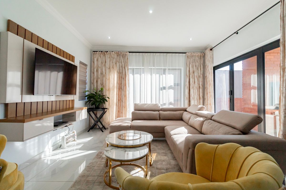 Bright and modern living room featuring a custom built-in media unit, large sliding glass doors for natural light, and polished tiled flooring.