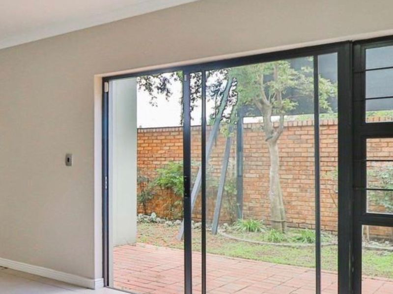 Bright living area featuring large sliding glass doors that open onto a private paved patio and garden space.