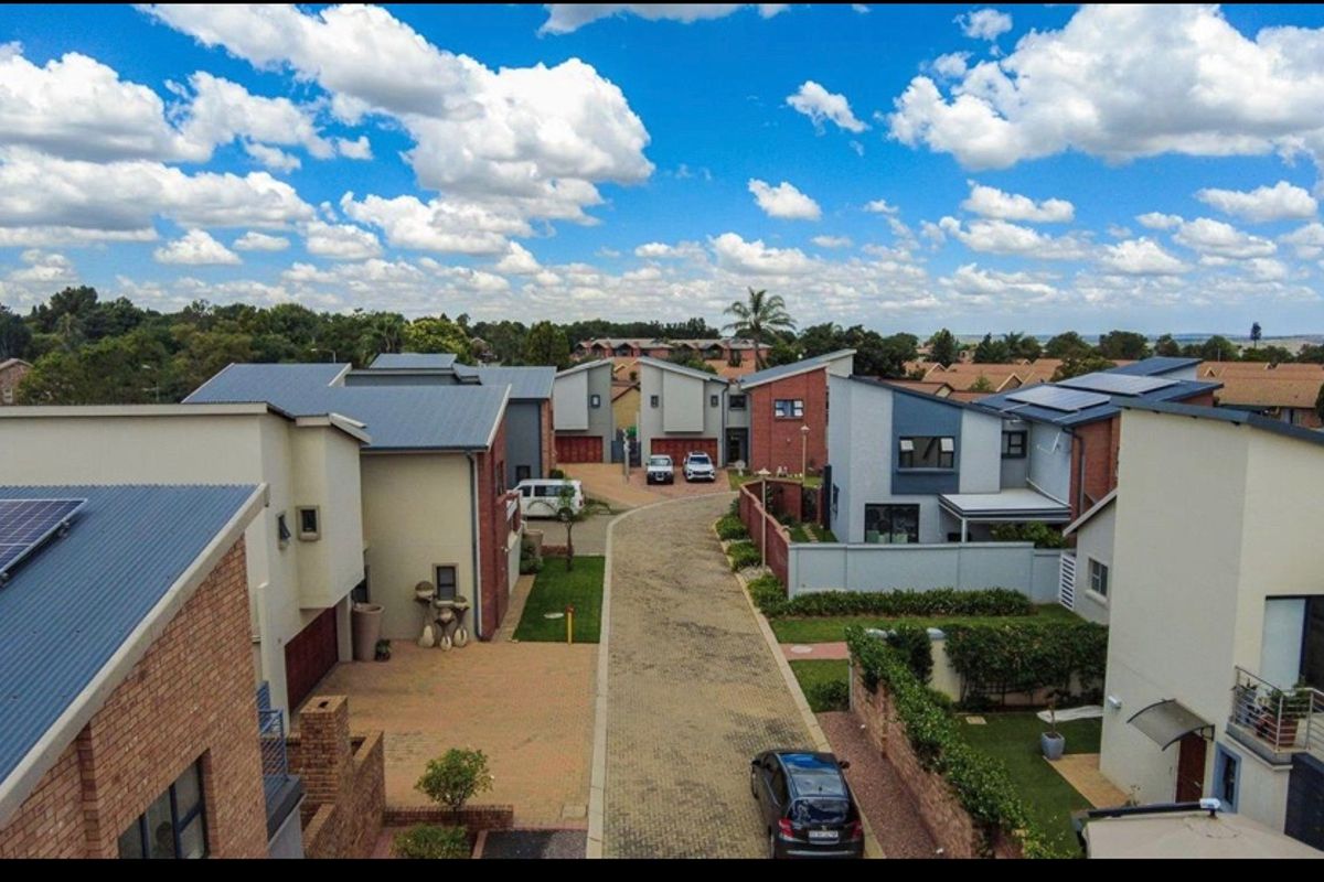 Aerial view of a modern residential estate featuring multiple homes with brick and rendered facades, paved driveways, and installed solar panels.