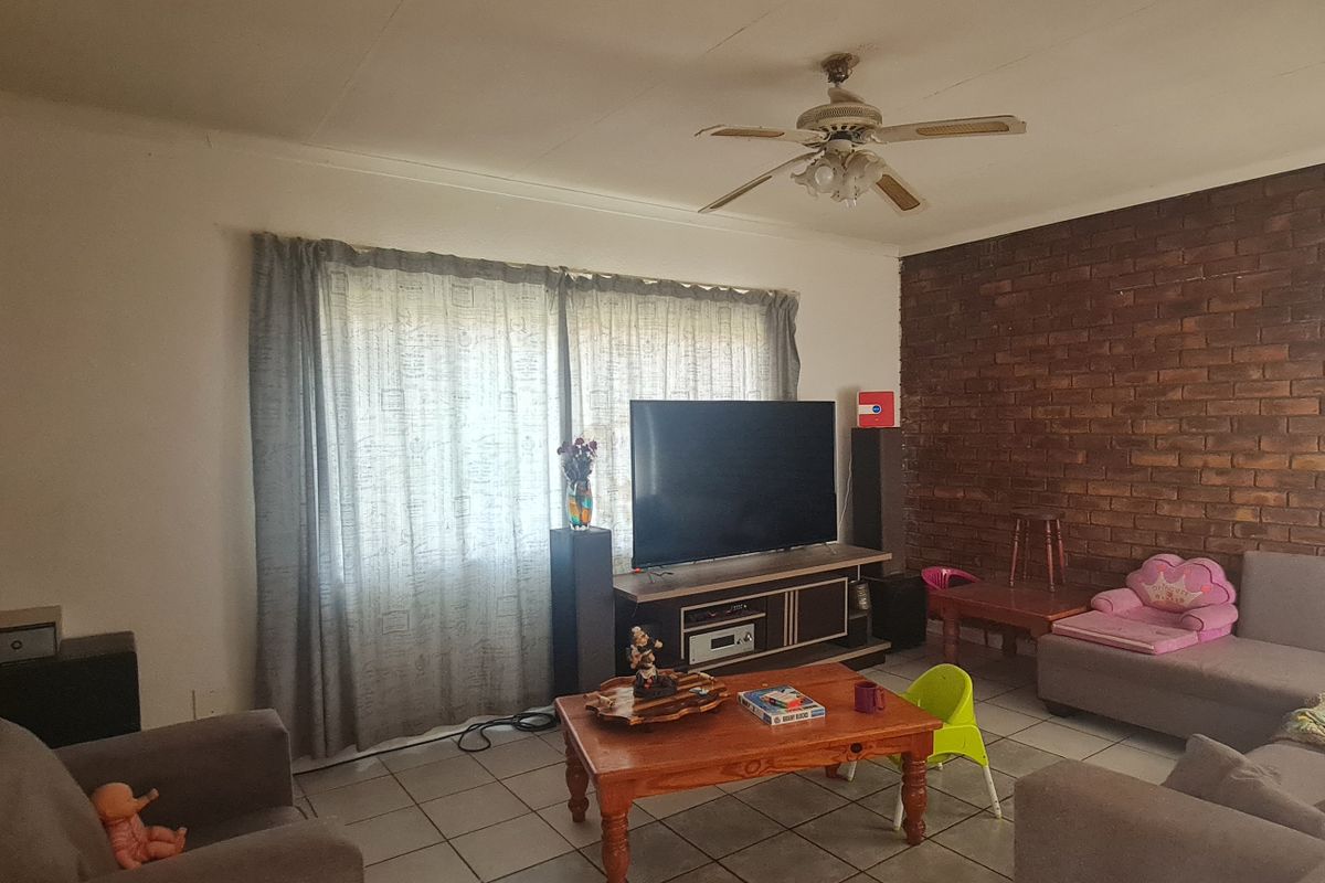 Living room featuring exposed brick feature walls, tiled flooring, and a ceiling fan.