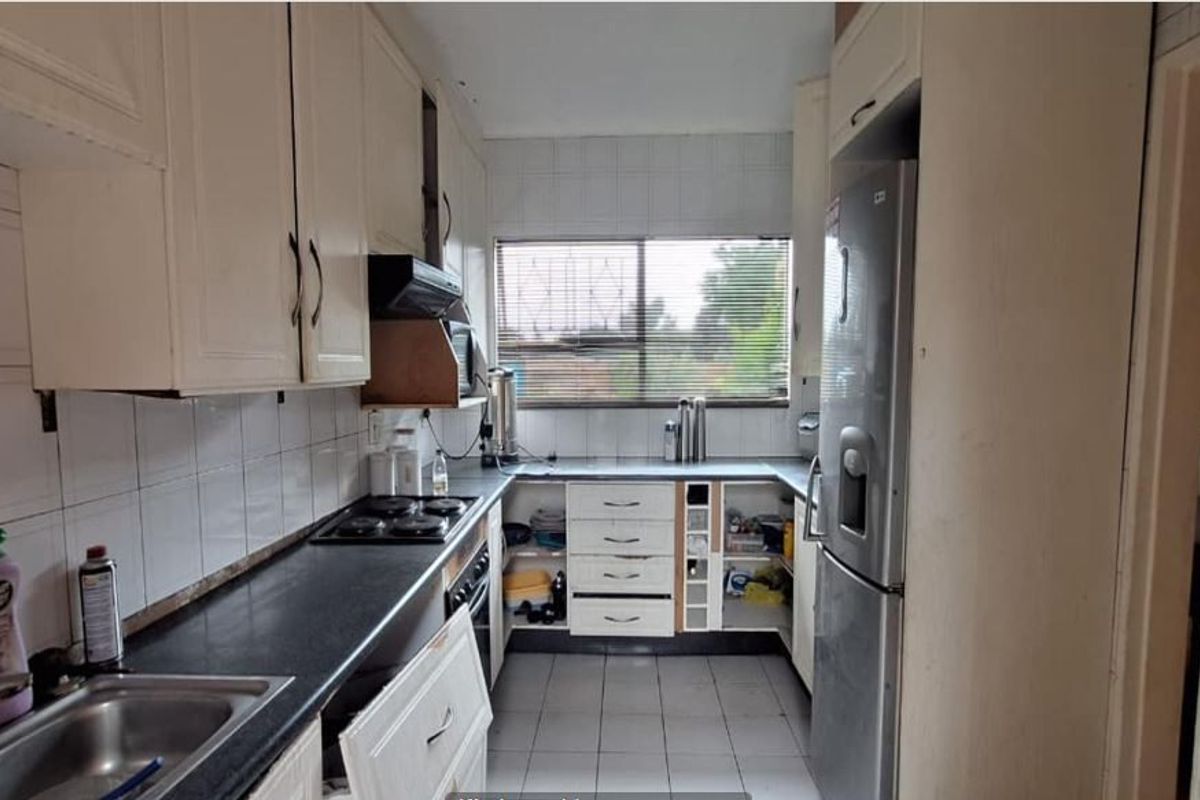 A functional kitchen featuring built-in cabinetry, laminate countertops, and a tiled splashback, currently showing signs of wear and requiring cosmetic updates.
