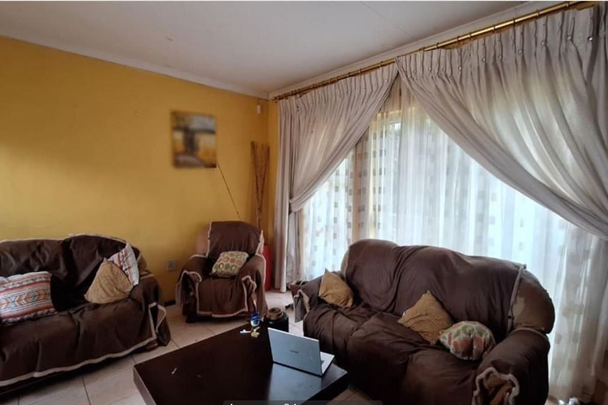 A living room featuring tiled flooring and large windows with curtain rails, offering a functional space ready for a modern update.