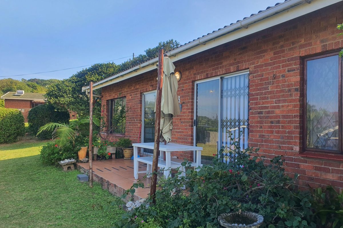 Rear view of the apartment featuring a brick facade, tiled patio area, and sliding glass doors with security gates.