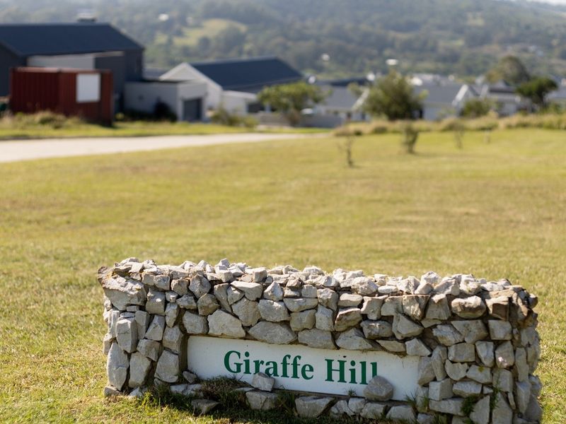 A view of the Giraffe Hill residential land development, featuring a stone-clad entrance sign and surrounding grassed landscape.