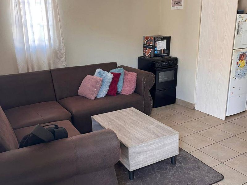 An open-plan living area featuring tiled flooring and a built-in storage cupboard, providing a functional and versatile space.
