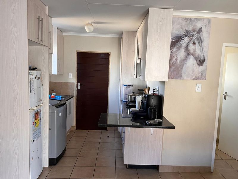 Functional kitchen featuring light wood-look cabinetry, dark granite countertops, and tiled flooring, providing a practical workspace with direct access to an adjacent room.