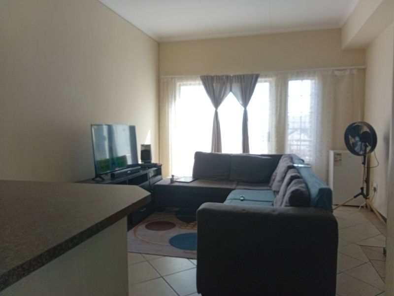 A living room area featuring tiled flooring and a sliding glass door providing natural light.