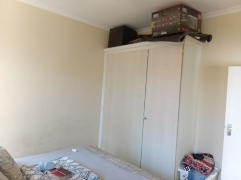 A bedroom featuring a built-in wardrobe with light wood-grain finish and decorative ceiling coving.