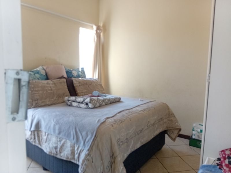 A standard bedroom featuring tiled flooring and a built-in cupboard, offering a functional space with neutral wall finishes.