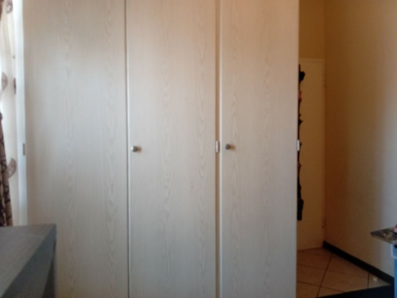A bedroom featuring light wood-finish built-in wardrobes with simple hardware.