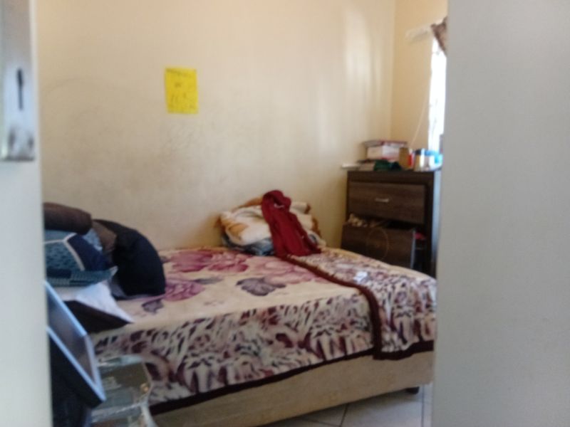 A bedroom interior featuring tiled flooring and standard wall finishes, currently showing signs of wear and requiring cosmetic updates.